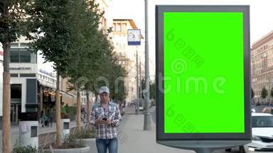 在一条城市街道上，一个男人点击广告牌附近的智能手机站